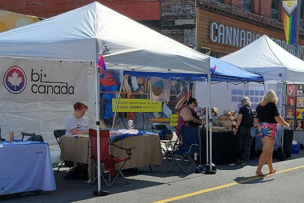 Volunteers at a Bi+ Canada booth during a street fair